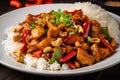 Kung Pao chicken on a bed of steaming white rice with spicy red peppers, diced peanuts, and crispy green onions