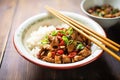 kung pao chicken with chopsticks placing a piece on rice Royalty Free Stock Photo