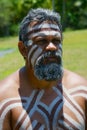 Portrait of aborigine actor with traditional face and body makeup in Tjapukai Culture Park in Kuranda, Queensland, Australia.