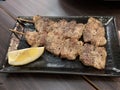 Kushiyaki Butabara, Charcoal-grilled pork belly with lemon on dish.