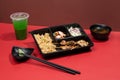KUSHIYAKI PREMIUM BENTO with mint margarita, sauce and chopsticks isolated on red background side view of japanese fast food