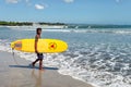 Kuta Beach in Kuta, Bali, Indonesia with a Surfer carrying a Surfboard Royalty Free Stock Photo