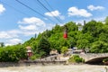 Kutaisi red cable car over Rioni river, lush green trees, residential houses and Upper station in the background Royalty Free Stock Photo