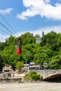 Kutaisi red cable car over Rioni river, lush green trees, residential houses and Upper station in the background Royalty Free Stock Photo