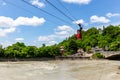 Kutaisi red cable car over Rioni river, lush green trees, residential houses and Upper station in the background Royalty Free Stock Photo