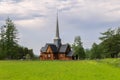 A vibrant green field and the historic Kvikne kirke, an old wooden church surrounded by lush green trees