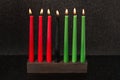 Kwanzaa festival concept seven candles red, black and green in candlestick on black background, copy space