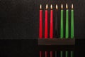 Kwanzaa festival concept seven candles red, black and green in candlestick with reflection on black background, copy space