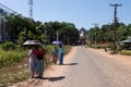 Kyaik Pun pagoda. People walking dressed in the traditional manner covering their heads from the strong sun with umbrellas. Bago,