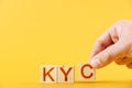 kyc. hand folds wooden blocks in the inscription kyc on an orange background.