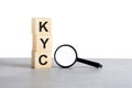 KYC - Know Your Client - text wooden cube blocks and magnifying glass on grey table