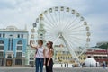 Kyiv UA, 19-07-2018. European city, entertainment ferris wheel on the square. Young girls tourists are photographed in the backgro