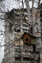 KYIV, UKRAINE - APR 21, 2022: Birdhouse on a tree near the apartment building on Poznyaky wich was destroyed by russian cruise Royalty Free Stock Photo