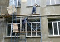 Building contractors on scaffolding are renovating, plastering, applying stucco on the facade