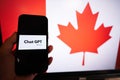 Kyiv, Ukraine - April, 2023: Hold smartphone with OpenAI Chat GPT against Canada flag on screen