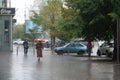 Heavy summer rain in Kyiv. People walks under umbrellas along wet streets