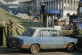 Selective blur on men, military soldier standing on a soviet car lada 2107 on Euromaidan barricades and tents after the revolution