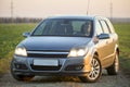 Kyiv, Ukraine - August 25, 2018: Young attractive long-haired woman inside shiny silver car at steering wheel on gravel empty road