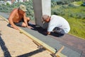 Roofers installing Asphalt Shingles on house roofing construction. Roofing Contractors laying Asphalt Shingles roof tiles