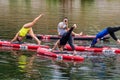 A group of young girls in the middle of the river perform sports exercises on swimming boards.