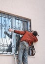 The man is installing steel security gates on the window. Window safety metal gates or window