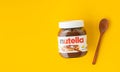 KYIV, UKRAINE - February 21: Nutella chocolate hazelnut spread in a glass jar with white cap next to wooden spoon and raw