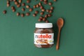 KYIV, UKRAINE - February 21: Nutella chocolate hazelnut spread in a glass jar with white cap next to wooden spoon and raw