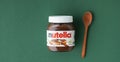 KYIV, UKRAINE - February 21: Nutella chocolate hazelnut spread in a glass jar with white cap next to wooden spoon and raw