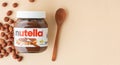 KYIV, UKRAINE - February 21: Nutella chocolate hazelnut spread in a glass jar with white cap next to wooden spoon and raw