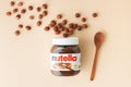 KYIV, UKRAINE - February 21: Nutella chocolate hazelnut spread in a glass jar with white cap next to wooden spoon and raw