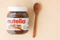 KYIV, UKRAINE - February 21: Nutella chocolate hazelnut spread in a glass jar with white cap next to wooden spoon and raw