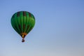 Hot air balloon in clear summer sky. Green balloon on blue background with copy space. Bright geometric design.