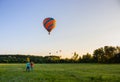 Hot air balloons in clear sky over field with people. Colorful balloons on aerial landscape background. Summer leisure. Royalty Free Stock Photo