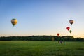 Hot air balloons in clear sky over field with people. Colorful balloons on aerial landscape background. Summer leisure.