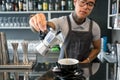 Barista pours coffee from the coffee pot inside contemporary design style cafe with bar Royalty Free Stock Photo