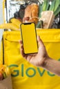 KYIV, UKRAINE - January 17: Glovo thermal food bag full of products from the grocery store. Female hand holds mobile phone with