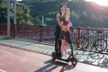 Kyiv, Ukraine - July 11, 2020. Pedestrian bridge. Attractive couple in love riding one electric push scooter together