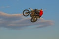 A brave biker jumps very high on a motorcycle and performs a stunt.