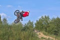 A brave biker jumps very high on a motorcycle and performs a stunt.