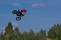 A brave biker jumps very high on a motorcycle and performs a stunt.