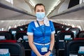 Kyiv, Ukraine - June 27, 2020: A flight attendant and a stewardess in a medical mask in the cabin of a Windrose airline prepares