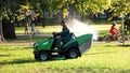 Lawn mower cutting grass in summer park. Royalty Free Stock Photo