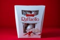Box of Ferrero Raffaello premium sweets produced by the Italian chocolatier Ferrero SpA on a red background, close up. Raffaello
