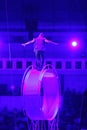 Circus performer / acrobat on top of spinning wheel of death / space wheel. Dangerous job.