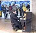 Homeless man playing piano on street with stray dog
