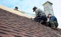 Roofer contractors are installing dimensional asphalt shingles from bottom up on the rooftop with