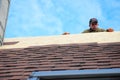 KYIV, UKRAINE - March, 11, 2019: Roofer laying asphalt shingles on house roof. Roofer with protection rope, safety kit on the