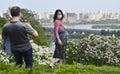 A man photographs a woman in a mask on a back ground of lilac and the left bank of Kyiv.