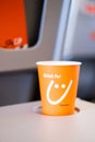 Kyiv, Ukraine - May 27, 2021: Orange paper cup with logo of Sky Up airline on Grey Tray table for passenger in plane Royalty Free Stock Photo