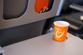 Kyiv, Ukraine - May 27, 2021: Orange paper cup with logo of Sky Up airline on Grey Tray table for passenger in plane Royalty Free Stock Photo